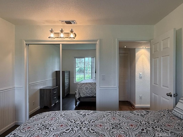 540 Pico Ave Unit 110, San Simeon, CA 93452 - bedroom featuring a closet, wood finished floors, baseboards, wainscoting, and a textured ceiling