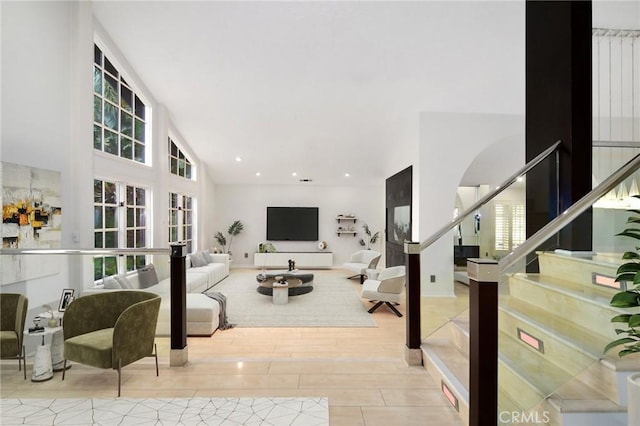 living room with stairs, wood finished floors, lofted ceiling, arched walkways, and recessed lighting