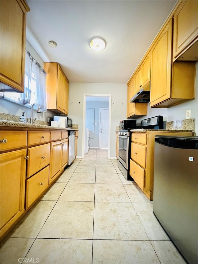 945 N Dickel St, Anaheim, CA 92805 - kitchen with stainless steel appliances, under cabinet range hood, washer / dryer, a sink, and light tile patterned flooring