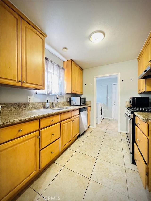 945 N Dickel St, Anaheim, CA 92805 - kitchen with stainless steel appliances, washing machine and clothes dryer, a sink, under cabinet range hood, and light tile patterned floors