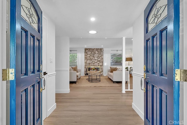 foyer entrance with light wood finished floors, baseboards, a fireplace, and recessed lighting