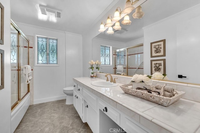 bathroom with toilet, crown molding, vanity, combined bath / shower with glass door, and a chandelier