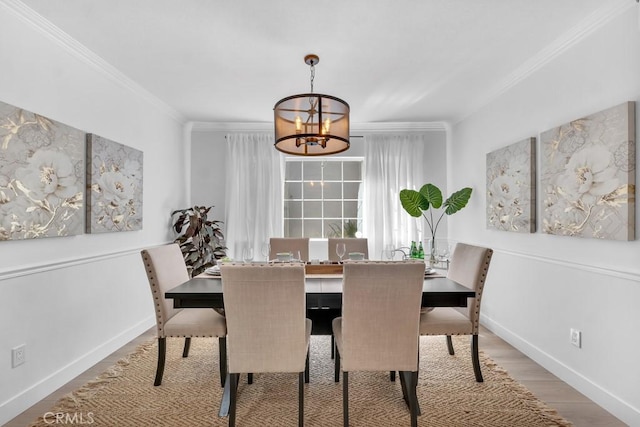dining room featuring a chandelier, ornamental molding, baseboards, and wood finished floors