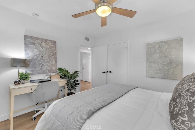 bedroom featuring wood finished floors, an office area, and a ceiling fan