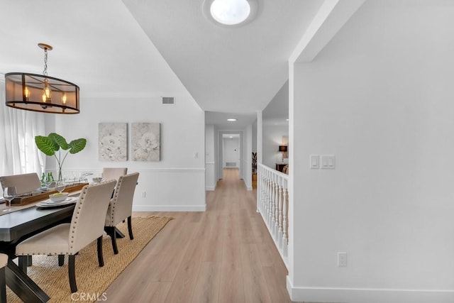 dining area featuring light wood-style flooring, baseboards, and a chandelier