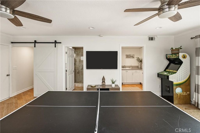 17252 Breda Ln, Huntington Beach, CA 92649 - recreation room with a ceiling fan, light wood finished floors, crown molding, a barn door, and recessed lighting