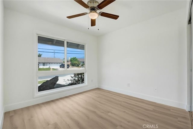 unfurnished room with baseboards, light wood-style flooring, and ceiling fan