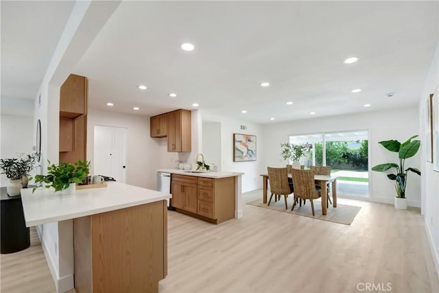kitchen with stainless steel dishwasher, a peninsula, light wood finished floors, and recessed lighting