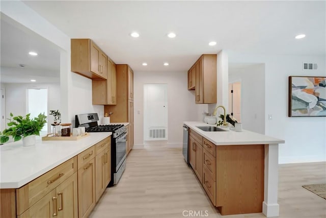 kitchen featuring stainless steel appliances, a sink, a peninsula, light wood-style floors, and recessed lighting