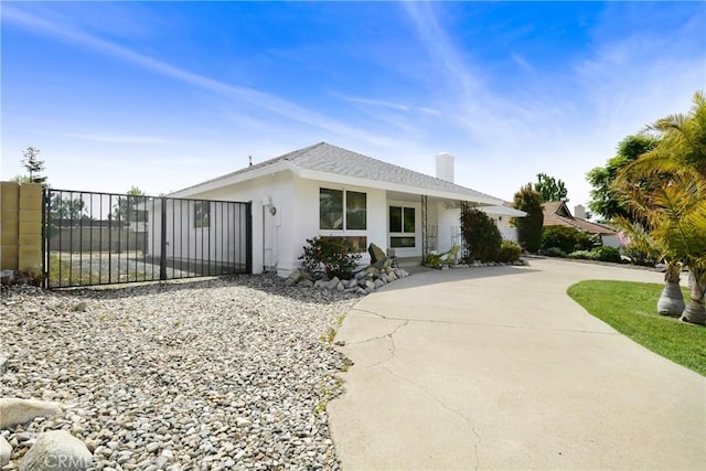 view of front of house featuring fence, a chimney, a gate, and stucco siding