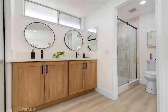 bathroom with a shower stall, wood finished floors, toilet, double vanity, and baseboards