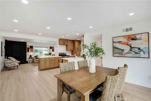 dining area with light wood-style flooring, recessed lighting, a fireplace, and baseboards