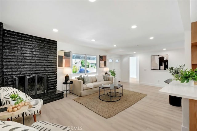 living room with light wood-style floors, recessed lighting, a fireplace, and baseboards