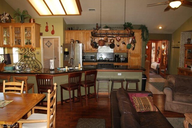 2205 Freeman Dr, Pine Mountain Club, CA 93225 - kitchen with vaulted ceiling, appliances with stainless steel finishes, a ceiling fan, dark countertops, and decorative backsplash
