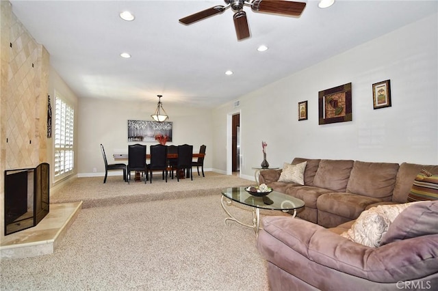 living area featuring light colored carpet, baseboards, a ceiling fan, recessed lighting, and a fireplace