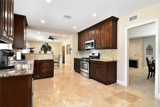 kitchen with appliances with stainless steel finishes, dark brown cabinetry, recessed lighting, backsplash, and a peninsula