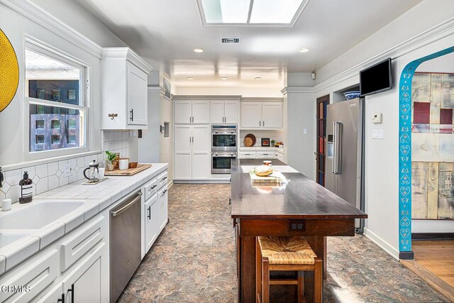 2707 Hermosita Dr, Glendale, CA 91208 - kitchen with appliances with stainless steel finishes, a kitchen bar, white cabinets, and recessed lighting