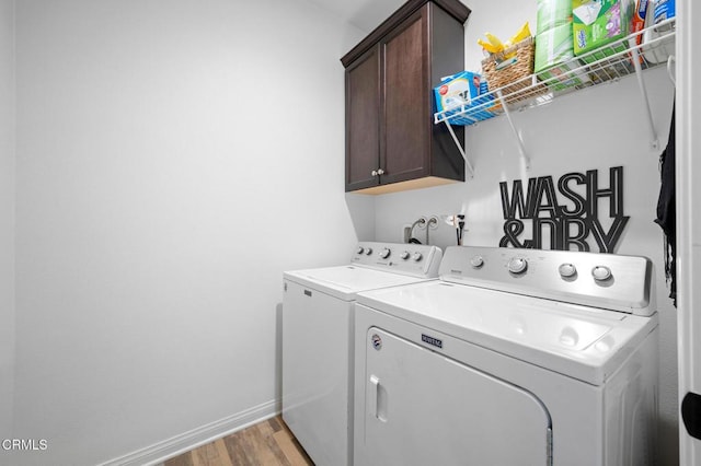 washroom featuring independent washer and dryer, light wood-style floors, cabinet space, and baseboards