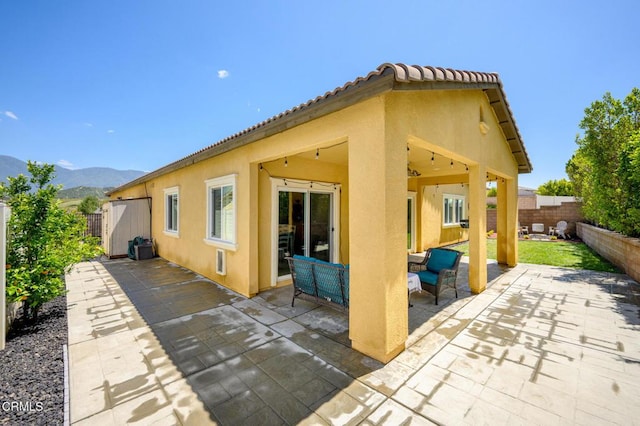 back of house with a patio area, stucco siding, a fenced backyard, and a mountain view