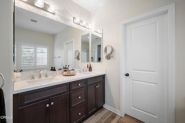 bathroom featuring wood finished floors, double vanity, and baseboards
