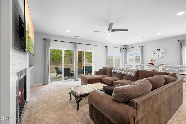 carpeted living area with recessed lighting, a ceiling fan, and a warm lit fireplace