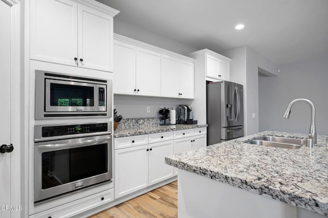 17837 Grapevine Ln, San Bernardino, CA 92407 - kitchen featuring stainless steel appliances, white cabinetry, light wood-style flooring, light stone counters, and recessed lighting