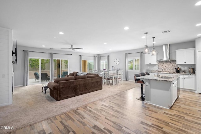 17837 Grapevine Ln, San Bernardino, CA 92407 - kitchen with wall chimney range hood, recessed lighting, open floor plan, white cabinetry, and a kitchen breakfast bar