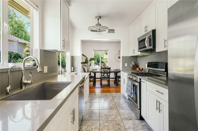 3316 Henrietta Ave, La Crescenta, CA 91214 - kitchen with stainless steel appliances, a sink, white cabinets, light marble finish flooring, and pendant lighting