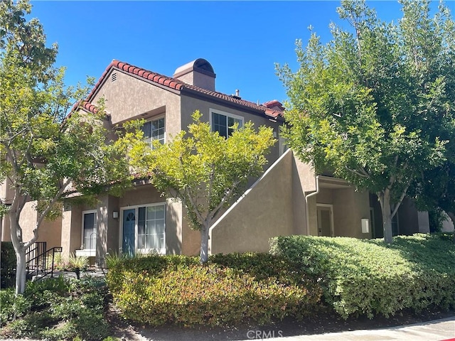 21203 Camelia Unit 34, Lake Forest, CA 92630 - view of side of property featuring stucco siding, a chimney, and a tiled roof
