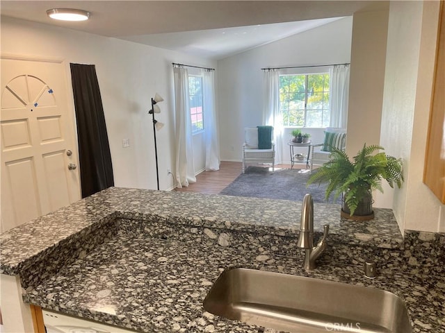 21203 Camelia Unit 34, Lake Forest, CA 92630 - kitchen featuring a sink, wood finished floors, dark stone counters, baseboards, and vaulted ceiling