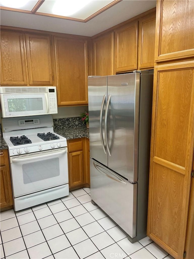 21203 Camelia Unit 34, Lake Forest, CA 92630 - kitchen with white appliances, light tile patterned floors, brown cabinets, and dark stone countertops