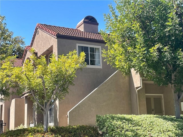 21203 Camelia Unit 34, Lake Forest, CA 92630 - view of home's exterior featuring a chimney, stucco siding, and a tile roof