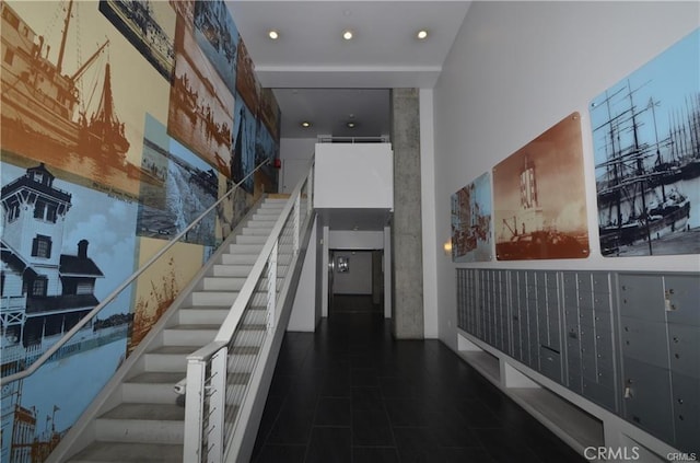 staircase featuring a towering ceiling, mail area, and recessed lighting