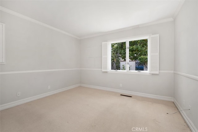 spare room with light colored carpet, crown molding, and baseboards