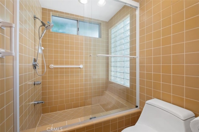 full bathroom featuring tiled shower, toilet, and plenty of natural light