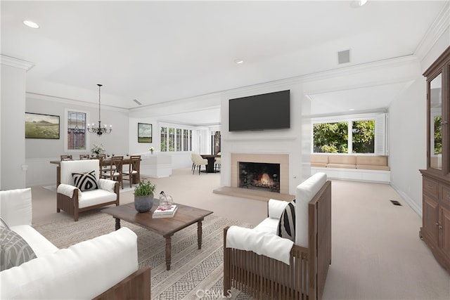 living area with crown molding, a chandelier, a warm lit fireplace, light colored carpet, and recessed lighting