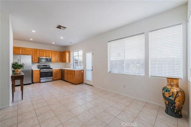 kitchen with appliances with stainless steel finishes, light countertops, a sink, light tile patterned floors, and recessed lighting