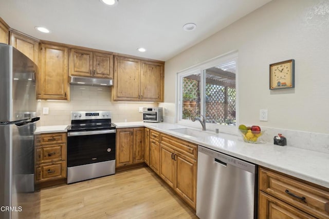 1093 Hickory View Cir, Camarillo, CA 93012 - kitchen with stainless steel appliances, under cabinet range hood, brown cabinetry, backsplash, and light countertops