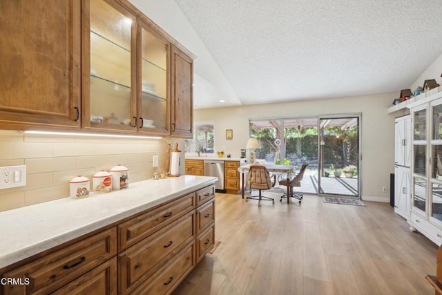 1093 Hickory View Cir, Camarillo, CA 93012 - kitchen with stainless steel dishwasher, brown cabinetry, light countertops, backsplash, and lofted ceiling