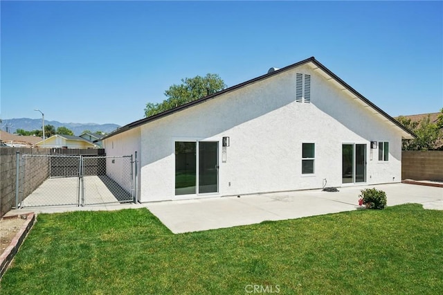 rear view of property with a patio, stucco siding, a gate, and a mountain view