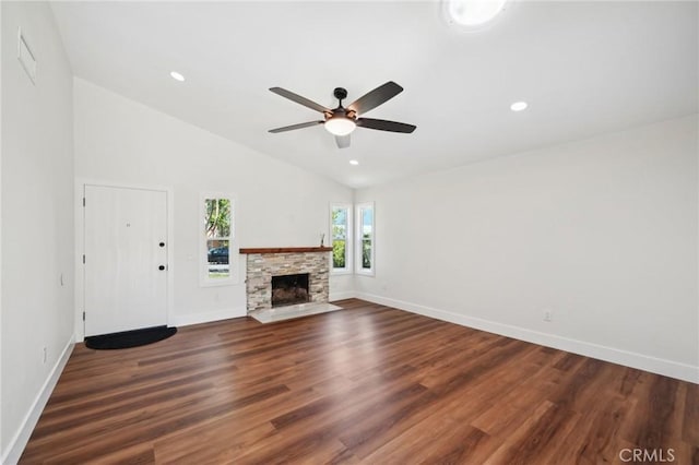 unfurnished living room featuring lofted ceiling, baseboards, ceiling fan, a stone fireplace, and wood finished floors