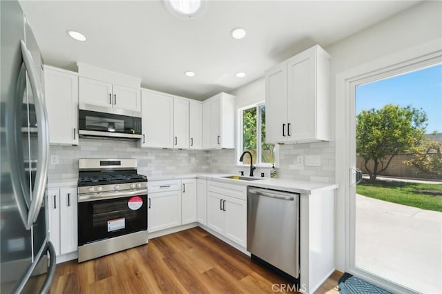 kitchen with stainless steel appliances, a sink, light countertops, backsplash, and recessed lighting