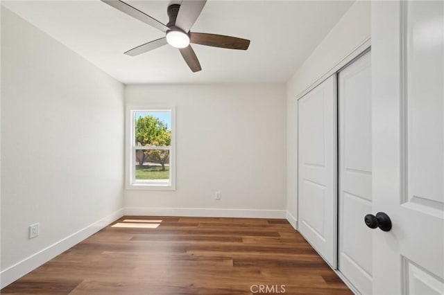 unfurnished bedroom featuring baseboards, a closet, wood finished floors, and a ceiling fan
