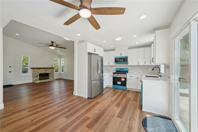 kitchen featuring appliances with stainless steel finishes, ceiling fan, a sink, open floor plan, and light countertops