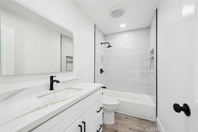 full bath featuring toilet, wood finished floors, vanity, and shower / tub combination
