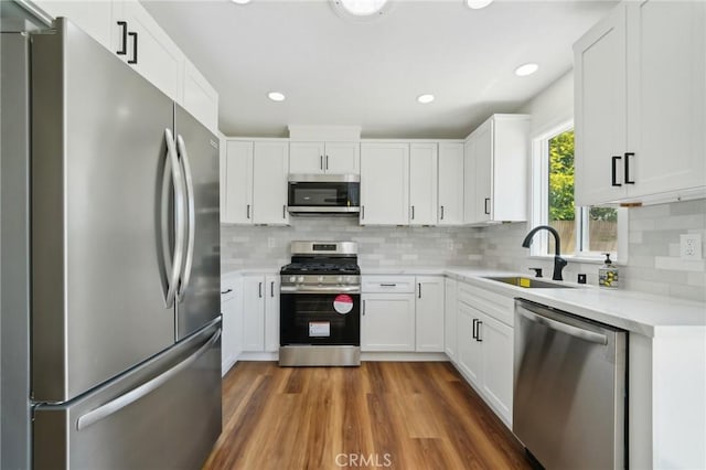 kitchen featuring appliances with stainless steel finishes, a sink, light countertops, white cabinetry, and decorative backsplash