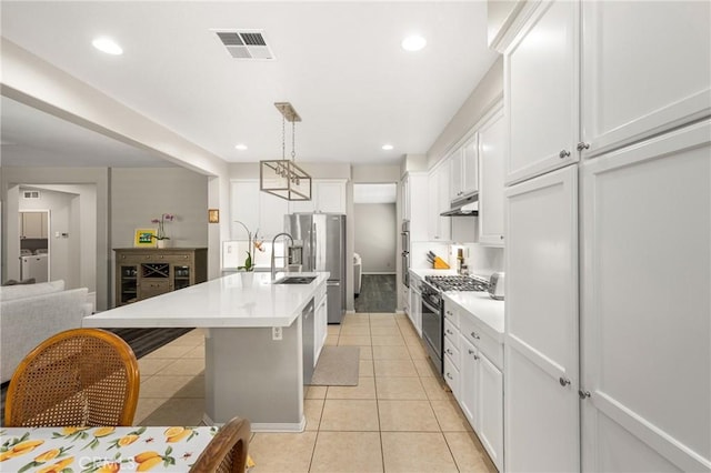 32748 Stonefield Ln, Temecula, CA 92592 - kitchen featuring appliances with stainless steel finishes, under cabinet range hood, light tile patterned floors, independent washer and dryer, and white cabinets