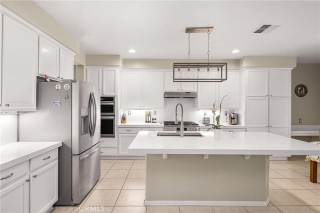 32748 Stonefield Ln, Temecula, CA 92592 - kitchen with under cabinet range hood, appliances with stainless steel finishes, light countertops, white cabinets, and light tile patterned floors