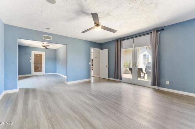 unfurnished living room with ceiling fan, french doors, wood finished floors, baseboards, and a textured ceiling