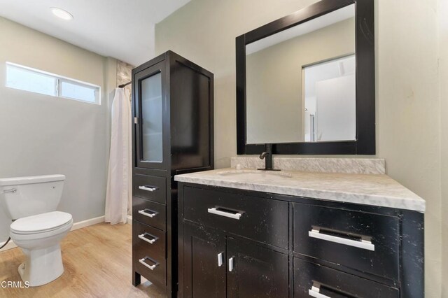 bathroom featuring toilet, wood finished floors, vanity, and baseboards